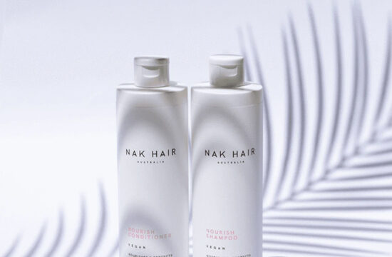 Two white bottles of Nak Hair Products with a palm leaf in the background, used by House of Hair in Langebaan