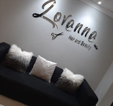 The reception area of Lovanne Hair and Beauty Salon in Langebaan, showing black couch, 3 white cushions with white back ground walls.