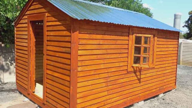 A vibrant wooden shed with a blue metal roof and a window, set in a garden environment.