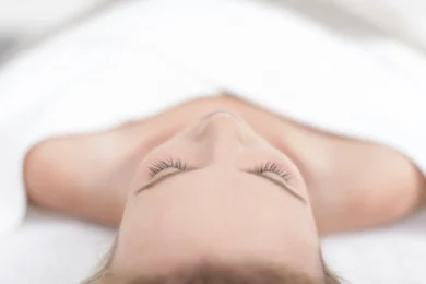 A lady is lying on a treatment table covered with white towels at a Wellness & Beauty facility in Langebaan.