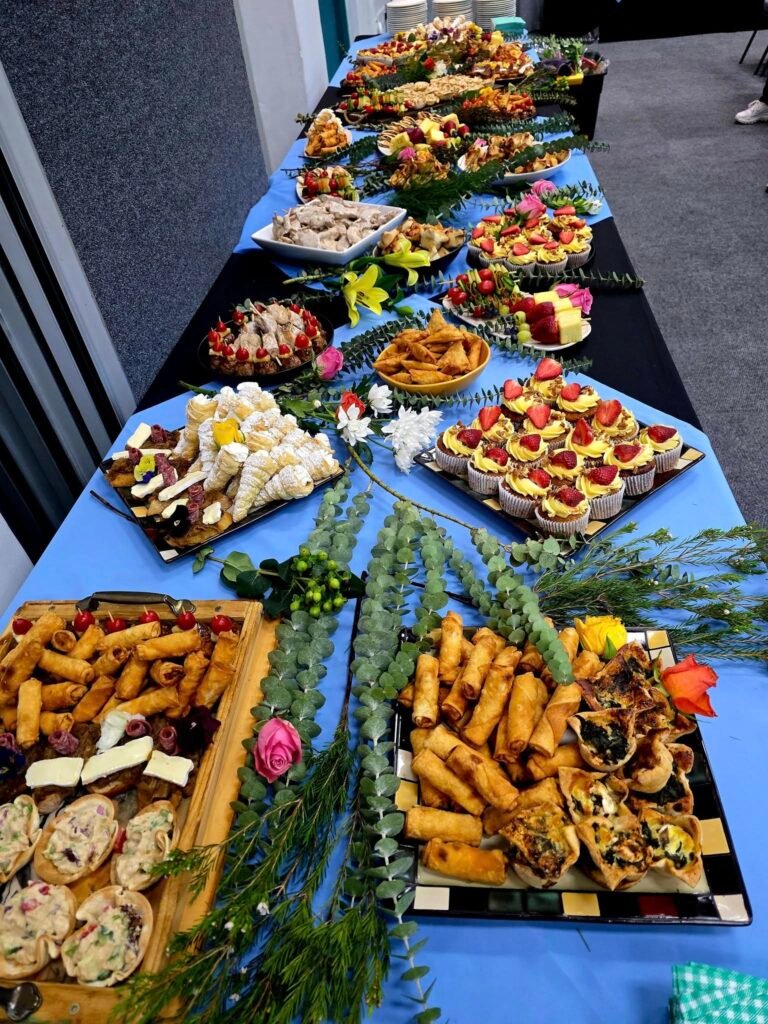 A long table with blue table cloth and differnt food on display for a catering event by Boeretroos Langebaan.
