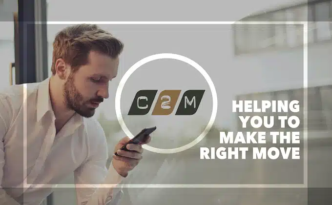 A man looks at his phone in this picture with the logo and signage in white letters and logo of C2M Chartered Accountants in the middle of picture .