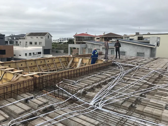 A house under construction under supervision of Deep-Rock Consulting Engineers in Langebaan, as workers work with steel and concrete for a first floor slab of a home.