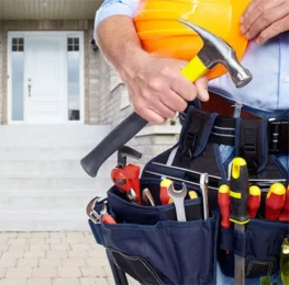 A handyman stands in front of a home with all his tools in hand and strap around him. Ready for Home Services & Maintenance work