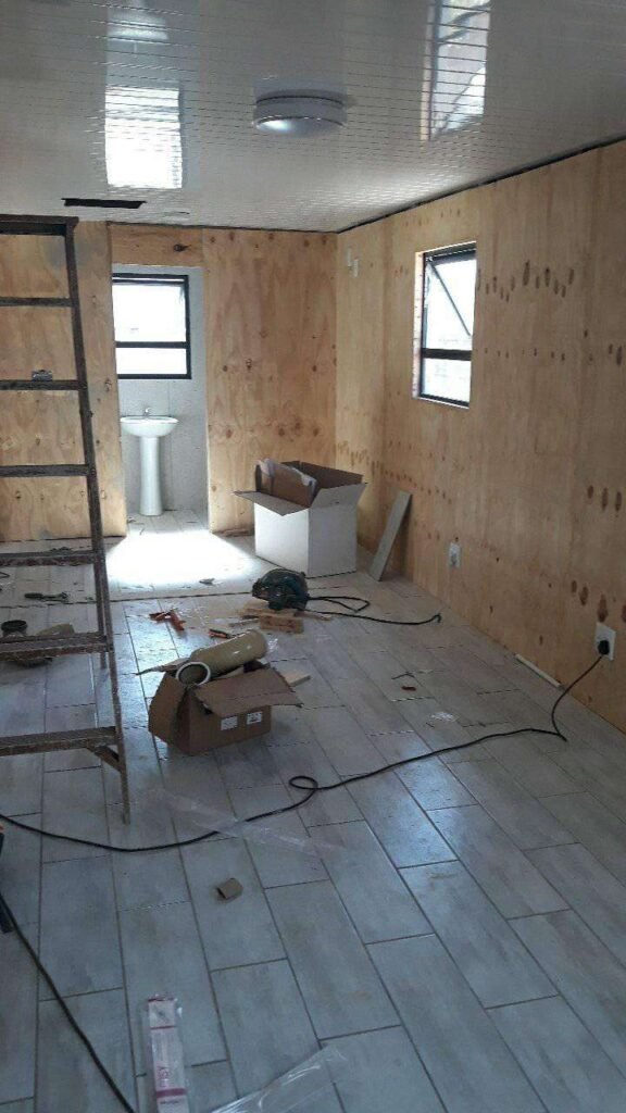 Still working in progress inside this wendy house by Laguna Wendys in Langebaan, showing electrical leads, ladder, wooden side panels, white ceiling and bathroom in a distance.
