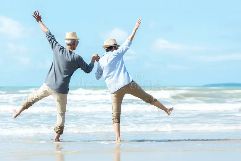 A Couple jump as they enjoy a stroll on the beach at Langebaan with joy