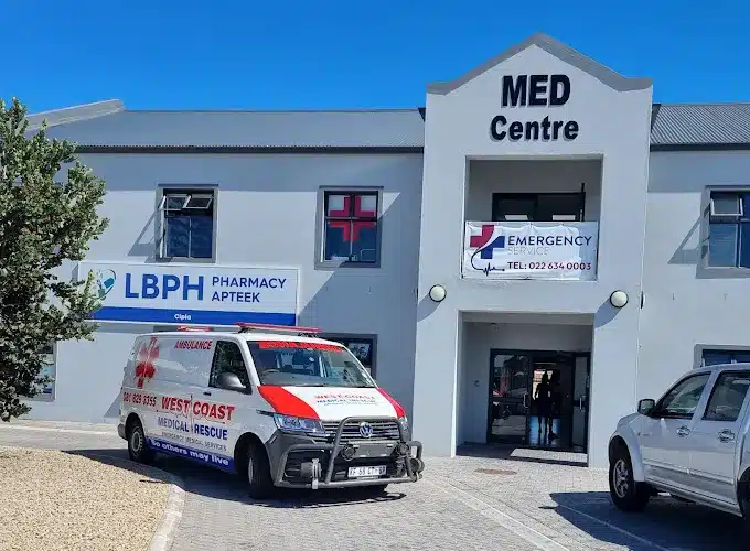 The front entrance to the Med Centre in Langebaan with ambulance of West Coast Medical Rescue, parked infront and signage of LBPH Pharmacy on the wall in blue.