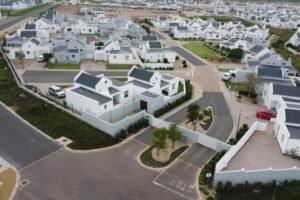 This picture shows the main entrance to one of the security complexes in Laguna Estates in Langebaan. It has white houses, charcoal roofs and lots of green landscape areas.