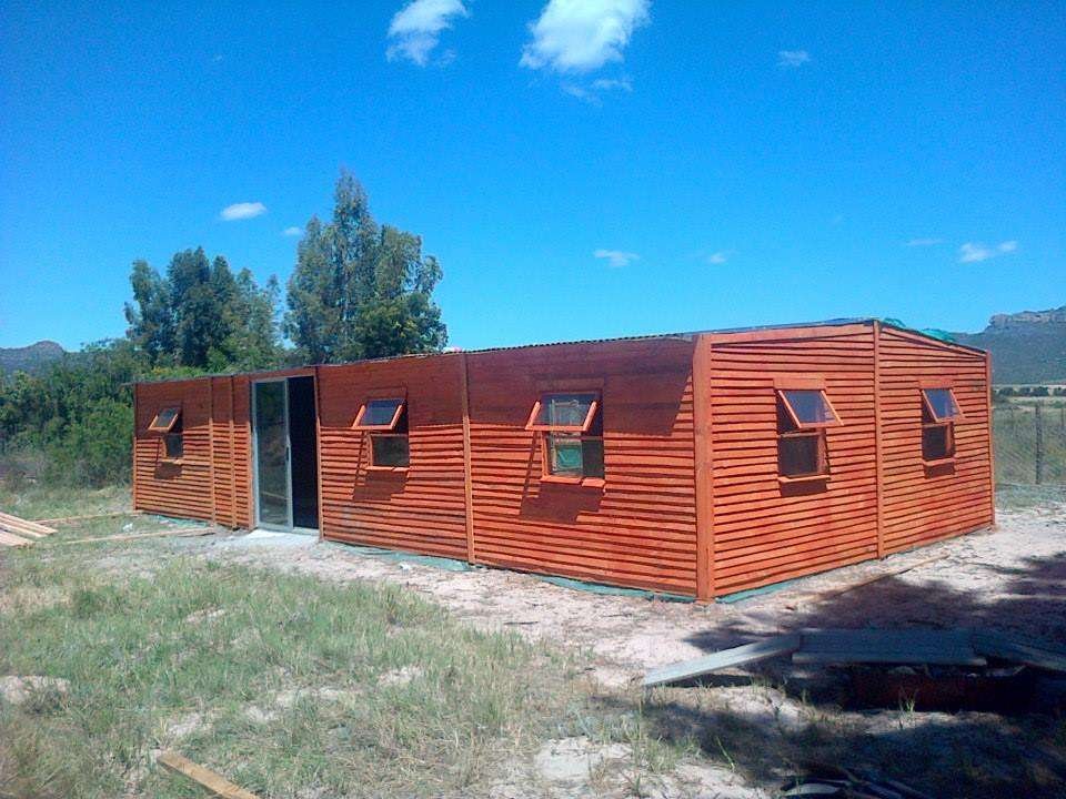 A wooden wendy house in the back yard of a property . Wooden slats to the side, sliding door and lots of windows, completed by Laguna Wendys in Langebaan