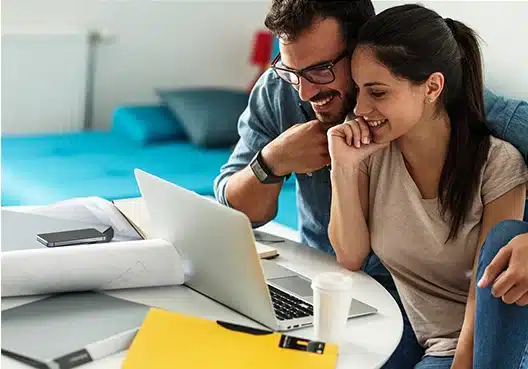 A Couple look at their laptop smiling as they received Financial advice from Old Mutual Langbeaan that makes them happy.