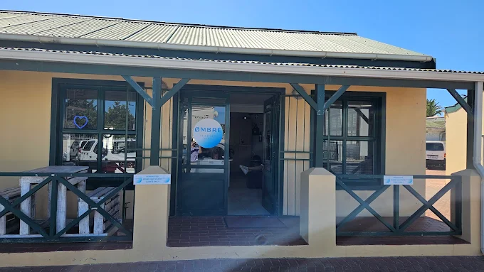 The front entrance of Ombre Hair salon in Langebaan with green doors, windows and yellow outside colour