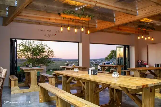 Wooden tables and seating at the The Table in Langebaan with views on the Long Acres Estate with outdoor area.
