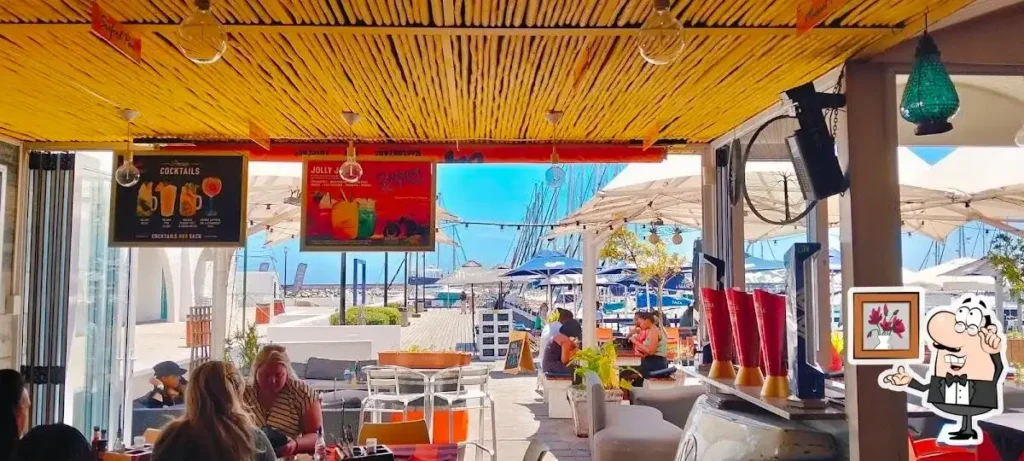 Wooden canopy protects the outside area of the Dockside Diner in Langebaan with white chairs, tables and a view towards the Marina at Club Mykonos.