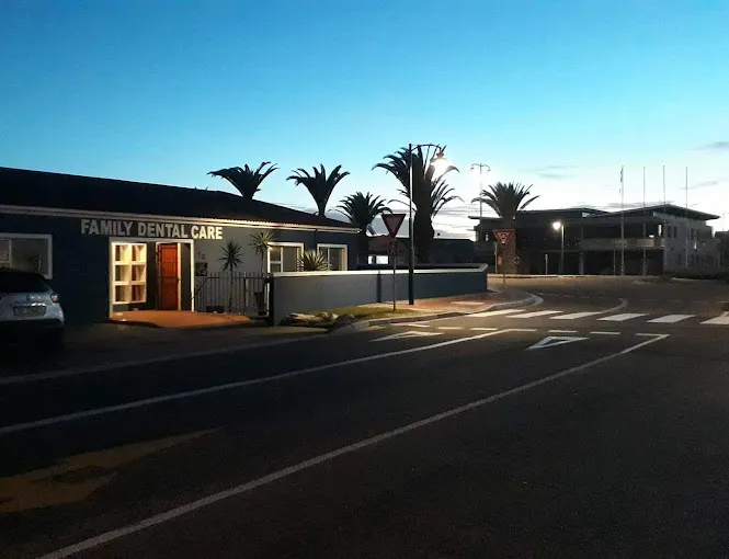 The practise of Dr Schalk Swart as a Dentist in Langebaan at night with light at the entrance and palm trees in a distance.