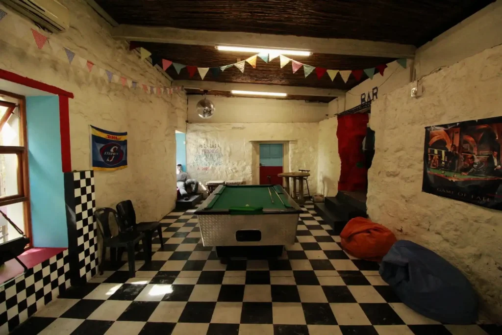 One of the room at FRIENDS Bar in Langebaan with white and black check floor tiles, green pooltable in the centre and colourful seating around the room