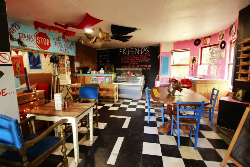 The interior of FRIENDS Bar & Diner in Langebaan with white and black floor, pink and blue walls and colourful tables and counter.