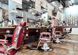 The interior of Headlines Barber Shop at Nautica Mall with lots of mirrors on the wall red barber chairs, wooden floors with products on shelves.