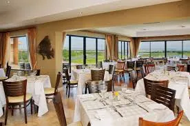 The interior of the Horizon Restaurant in Langebaan with white table cloths, silver cutlery and great view over golf course.