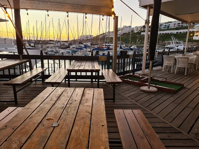 Deck with wooden seating at the Kapstadt Brauhaus at sunset with boats in background. Good entertainment at Langebaan Restaurants