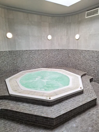 A jacuzzi full of water in a tiled room with floors and walls tiles in grey at La Vita Spa in Langebaan