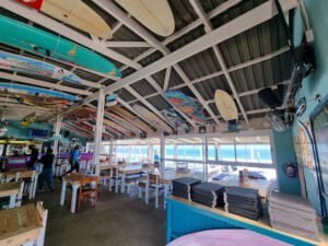Interior of Marc's Beach Bar with view of Langebaan lagoon with surfboards atteched to the ceiling of this restaurant and bar.
