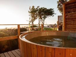 An outside wooden jacuzzi, filled with water, on a wooden deck with distance view at the Mint Wellness Spa in Langebaan.