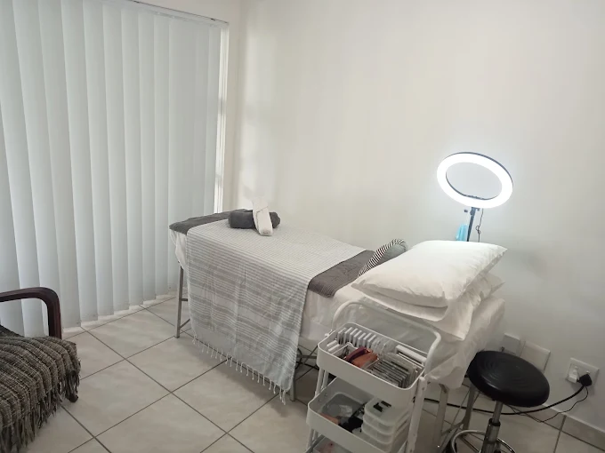 White room with white treatment bed, light and white tray on white floor at Moi Beautifully You in Langebaan.