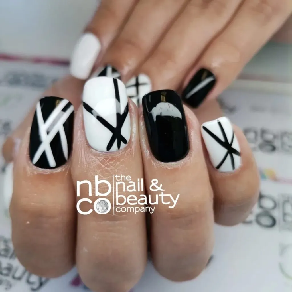 Nails done in different patterns of white and black, each nail with own design by The Nail & Beauty Company in Langebaan with white logo
