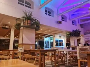 The interior of Rocxi's Beach Bar in Langebaan with wooden floors, tables and chairs, plants on pillars and white ceiling for funky look.