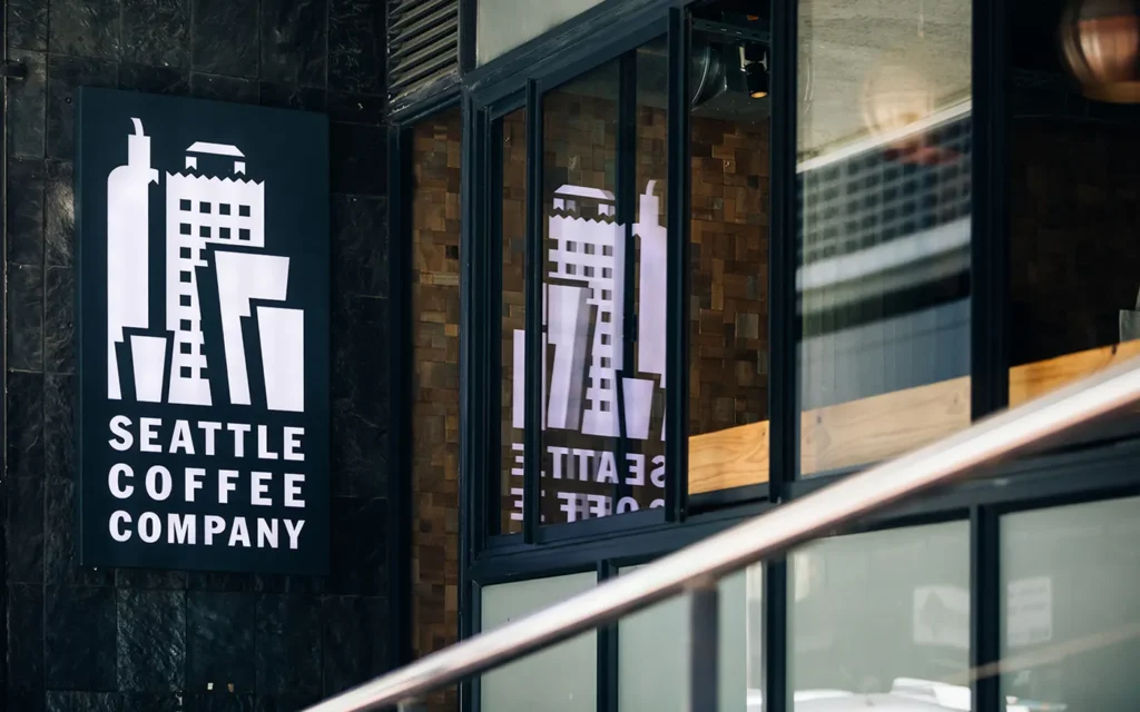 The logo in white reflecting in glass door at Seattle Coffee Company in Langebaan.