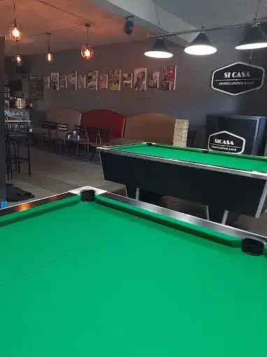 Two pooltables with green cloth are visible with seating in the background inside SiCasa Sports Lounge & Bar in Langebaan.