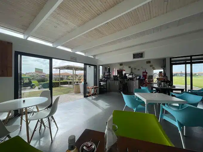 A picture of the interior of Soldato Cafe with views on the golf course in Langebaan. Mix of seating options with colourful chairs.