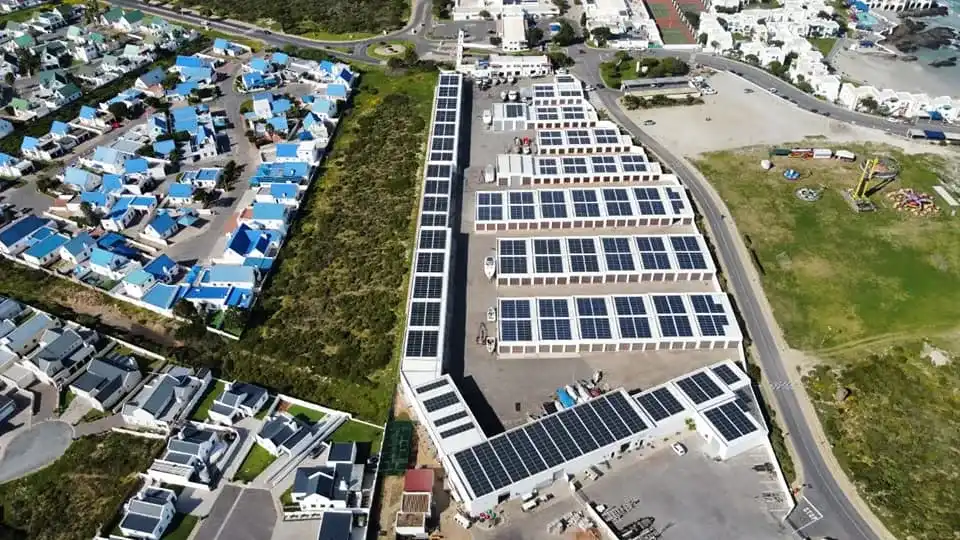 A distance view of all the roofs at Langebaan Boatyard with solar panels on top and the view of the town in a distance.