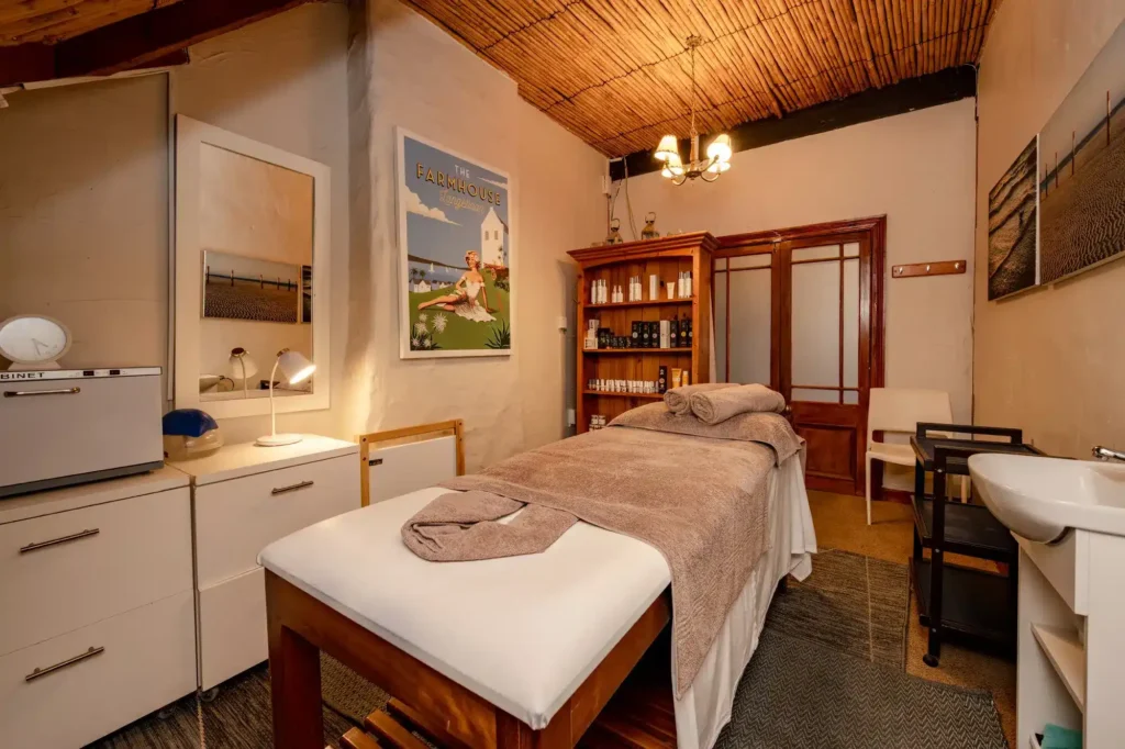 The interior of the Mint Wellness Spa in Langebaan, with table covered with towels, wooden ceiling, merchandise on display on wooden shleves and lots of white cubboards and decorations.