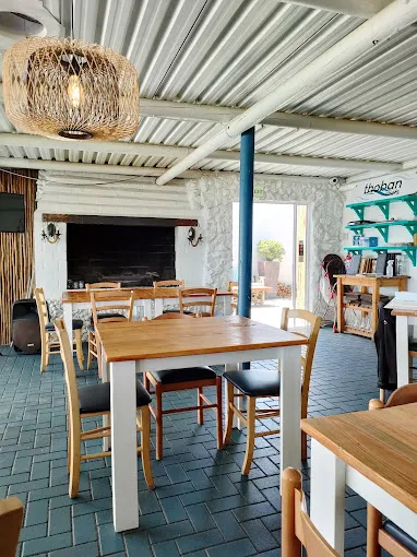 Interior of Toban Chef's Restaurant, well known for Great Seafood Langebaan Restaurants with wooden white tables, chairs ceiling and shelves on the wall.