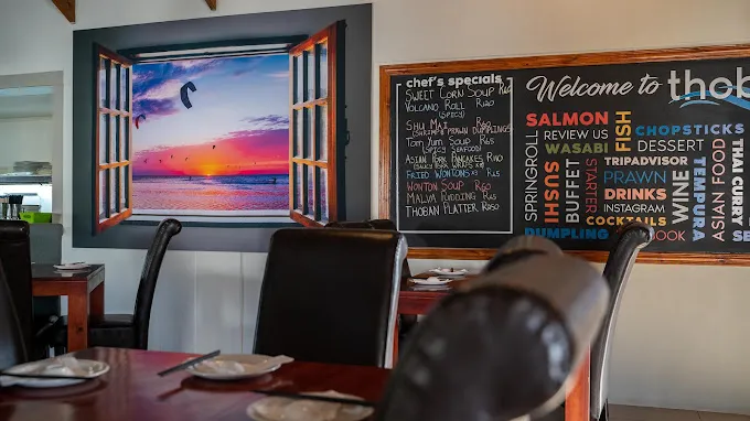 The interior of Thoban Chefs Restaurant in Langebaan with window with sunset and menu displayed on blackboard.
