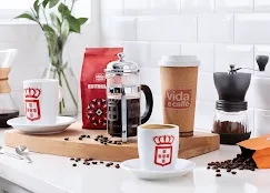 Two white mugs on a white table with foam cup, beans and coffee filter on a wooden plate at Vida e Caffee Coffee Shop in Langebaan