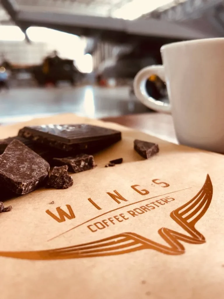 A Coffee mug, paper with the logo on it with choclate brownies at Wings Coffee Roasters in Langebaan.