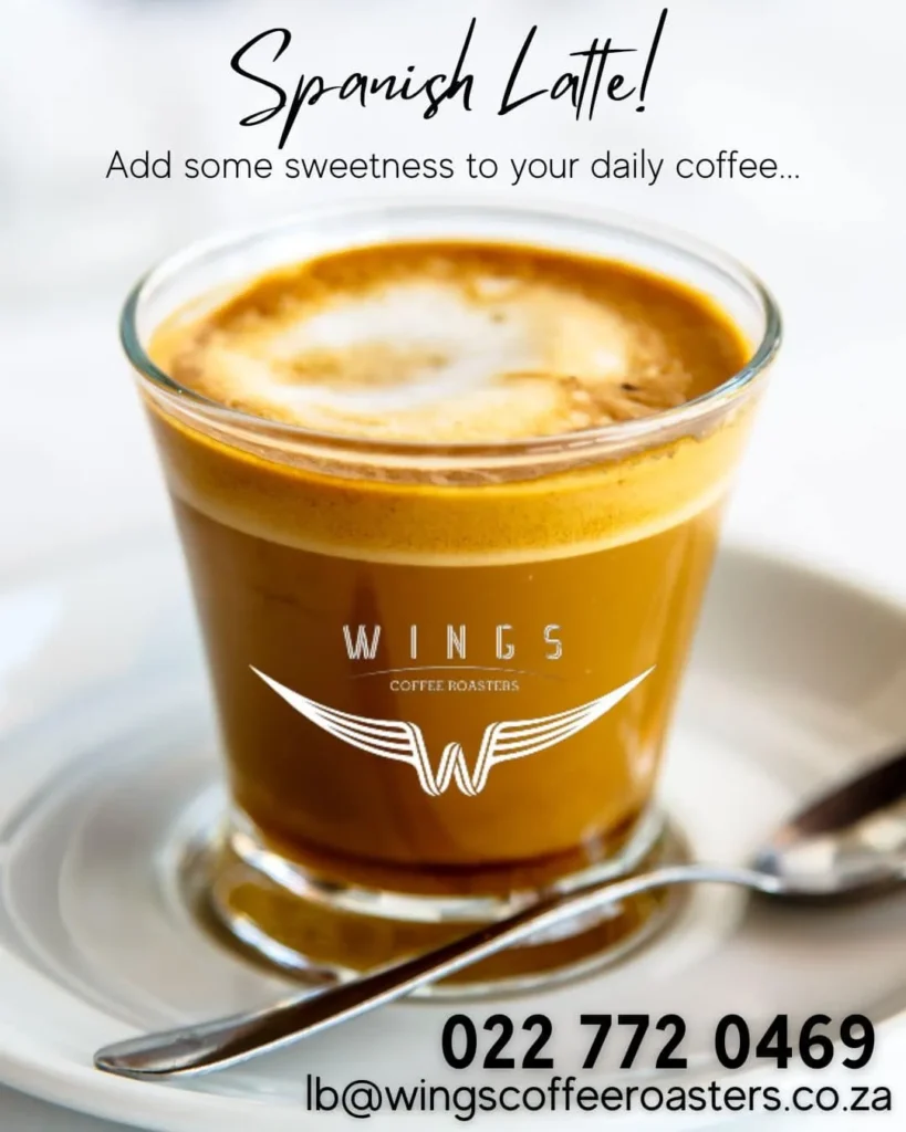A branded glass with Spanish latte and teespoon on a table at Wings Coffee Roasters in Langebaan.