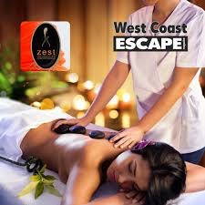 A lady lies on a treatment table while assistant is giving a stone massage to her back at Zest health & Beauty Spa in Langebaan